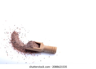 Himalayan black ground salt in a wooden cup on a white background.