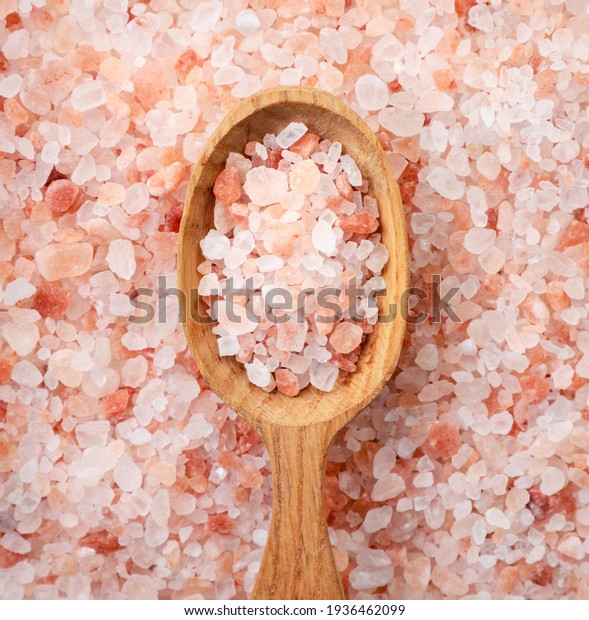 Himalayan pink salt in a spoon on a salt background\
close-up. Top view