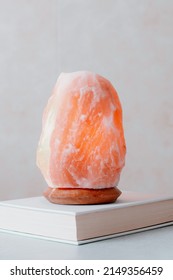 Himalayan Salt Lamp On Table With Book, Stress Control, Calming Home Decor. Natural Salt Lamp To Reduce Stress And Purify Air