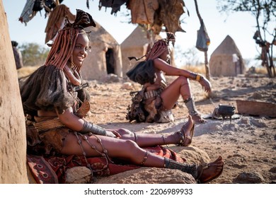 Himba women sitting outside their huts in a traditional Himba village near Kamanjab, northern Namibia, Africa.