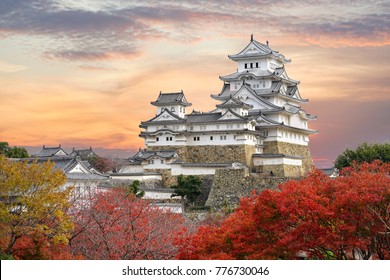 Himeji Castle and red maple leaves in evening sunlight and twilight sky in Himeji city, Hyogo prefecture of Japan.