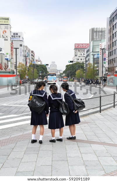 Himeji,\
Japan - November 20, 2016: Students are waiting to cross the street\
in the early morning near Himeji castle,\
Japan