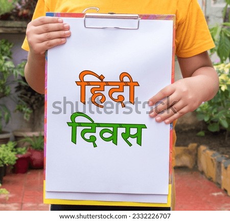 Hindi Diwas means Hindi Language Day word or text written on white paper board held with hand of kid or child.