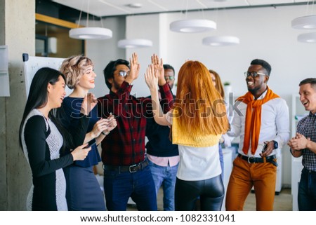 Hindo guy and Caucasian woman with red hair are giving high five to each other with two hads among their friends. good meeting