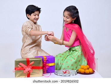 Hindu Brother and sister  in ethnic wear holding Indian sweets and gift box on the occasion of Raksha Bandhan festival - Shutterstock ID 2019826502