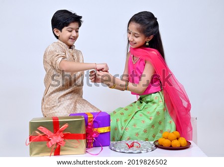 Hindu Brother and sister  in ethnic wear holding Indian sweets and gift box on the occasion of Raksha Bandhan festival