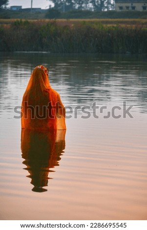 Hindu devotee offering prayers to sun god standing in water according to hindu rituals during Chhath Puja Festival. Chath Puja rituals                             