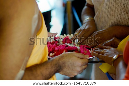 Hindu devotee touch flowers as offering to God during prayers,as the priest hold the plate 