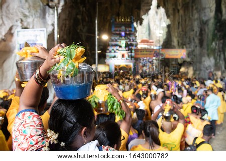 Hindu devotees entering Batu Caves during Thaipusam festival in Kuala Lumpur, Malaysia. Selective focus on woman on the left. Bokeh effect.