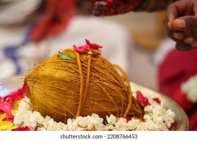 Hindu Indian wedding ceremony with coconut, yellow thread  colorful flowers - Shutterstock ID 2208766453