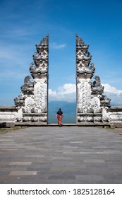 Hindu Lempuyang temple gates Instagram famous location for tourists taking solo photograph wearing Sarong with blue background sky in Bali, Indonesia
