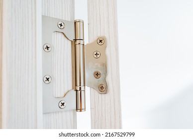 The hinge of the door is shot close-up, steel hinges are attached to the jamb of the doorway, cross-shaped screws are screwed into the door, interior details. High quality photo