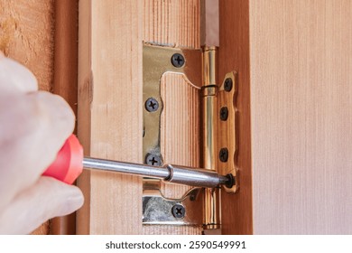Hinge leaf aligned on door frame, showcases screw being driven into pilot hole for door installation highlighting flush mounting and fastener placement.