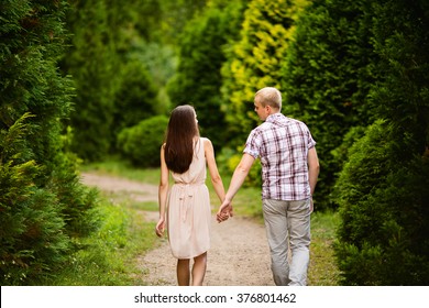 Hip Couple Holding Hands And Walking In A Park