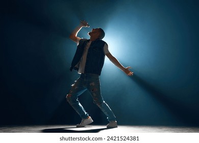 Hip hop artist performing his new song highlighted by striking beam of light on stage in smoky venue. Concept f music and dance, lifestyle, festivals, concerts, self-expression and hobby. Ad - Powered by Shutterstock