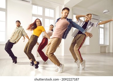 Hip hop dance crew rehearsing in modern light studio. Smiling young people having dancing class. Group of happy, beautiful, talented dancers in trendy casual wear all together practising new choreo