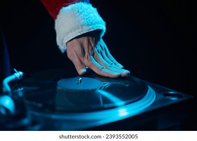 Hip hop DJ in red Santa costume scratching a vinyl record on turntable deck - Shutterstock ID 2393552005