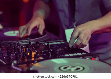 Hip hop DJ scratches vinyl records on turntables. Hands of disc jockey scratching record on turn table player in close up