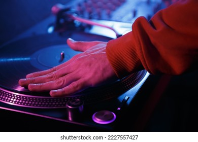 Hip hop DJ scratching records on turntables. Club disk jokey scratches vinyl disc on turn table in night club - Shutterstock ID 2227557427