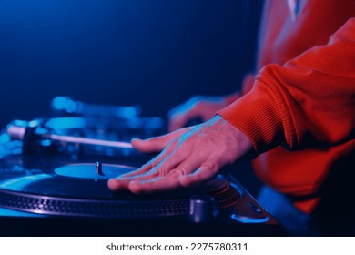 Hip hop DJ scratching vinyl disc on turntable. Disc jockey scratches record on party in night club
