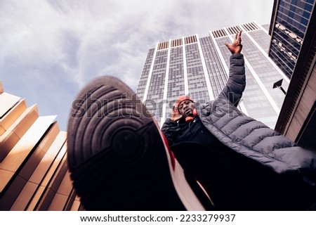 hip hop man walking above the camera lens under skyscrapers - stylish african american dj performing on street