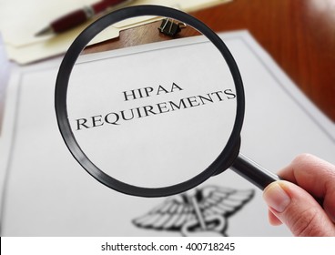HIPAA healthcare requirements document with hand holding a magnifying glass                              