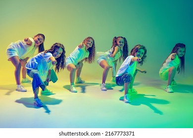 Hip-hop dance, street style. Group of children, little girls in sportive casual style clothes dancing in choreography class isolated on green background in neon light. Concept of music, fashion, art - Shutterstock ID 2167773371