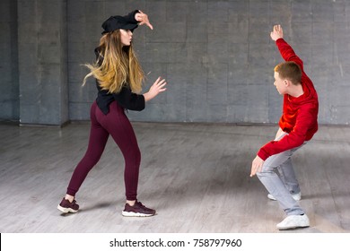 Hip-hop Dancers In Action. Young Couple Of Casual Dancers Performing Modern Dance On Studio Background. School Of Dance Art.