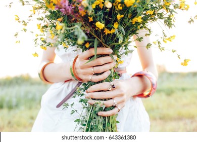 A hippy girl holding a bouquet of wildflowers in her hands