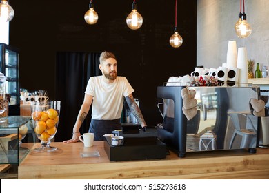 Hipster barista standing behind the bar at coffee shop