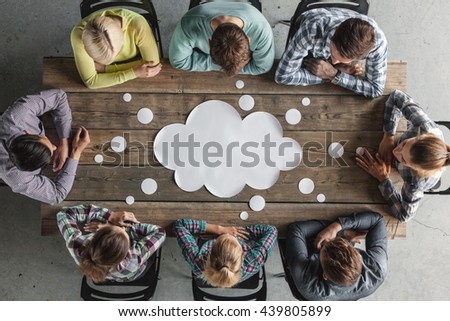 Hipster business teamwork brainstorming planning meeting concept, people sitting around the table with white paper shaped like dialog cloud