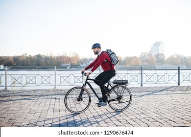 Hipster businessman commuter with electric bicycle traveling to work in city.