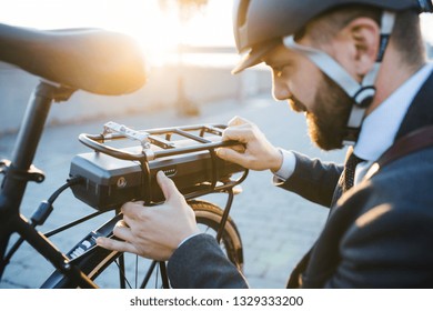 Hipster Businessman Commuter Setting Up Electric Bicycle In City.