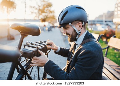 Hipster Businessman Commuter Setting Up Electric Bicycle In City.