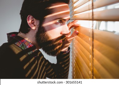 Hipster businessman peeking through blinds in his office