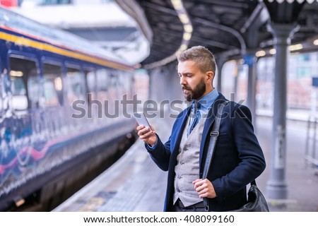 Hipster businessman with smartphone, waiting at the train platfo