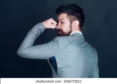 Hipster chose small size jacket, seam torn under armpit. Guy posing in counterfeit or fake brand. Man with beard wears jacket with hole on dark background. Bad quality of clothes concept.