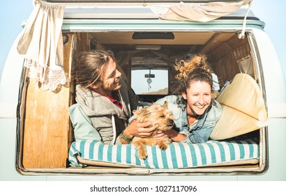 Hipster couple with cute dog traveling together on vintage mini van transport - Indie life style inspiration concept with hippie people on minivan adventure in relax moment - Bright warm retro filter