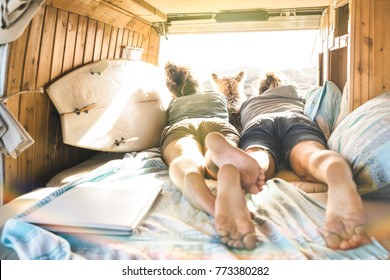 Hipster couple with cute dog traveling together on vintage van transport - Life inspiration concept with hippie people on minivan adventure trip watching sunset in relax moment - Warm sunshine filter