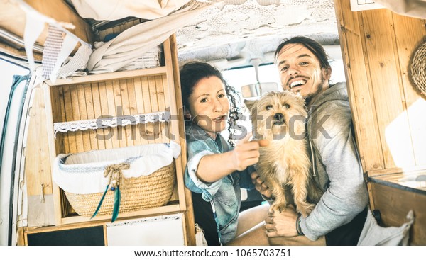 Hipster couple with cute dog traveling together on\
oldtimer mini van transport - Travel lifestyle concept with indie\
people on minivan adventure trip having fun in relax moment -\
Vintage retro filter