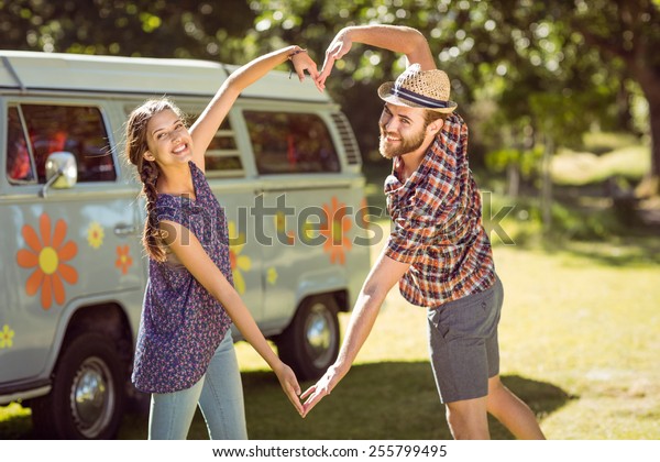 Hipster\
couple making heart with arms on a summers\
day