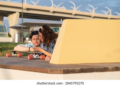 Hipster couple with smartphone relax together lying on longboard. Trendy young man and woman sharing social media, browsing websites or do online shopping on mobile phone outdoors using 5g internet - Powered by Shutterstock