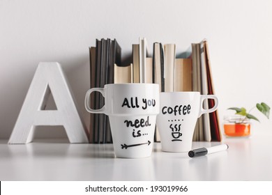 Hipster cup of coffee on a books library./ Two white coffee mug with diy decoration. 