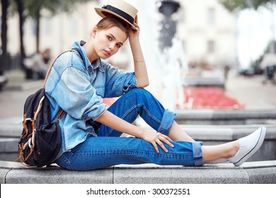 hipster fashion girl in jeans hat in her hand. outdoor color portrait