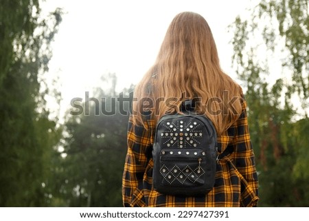 Hipster girl with backpack in woods. Traveler background. Tourist summer lifestyle. Blurred. Blonde curly hair. 