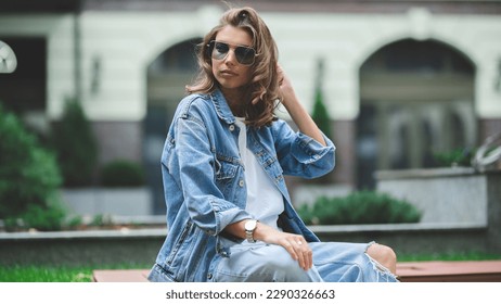 Hipster girl in clean white t-shirt and jeans posing against the background of buildings, minimalist urban clothing style - Powered by Shutterstock