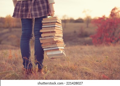 Garota hipster segurando uma pilha de livros