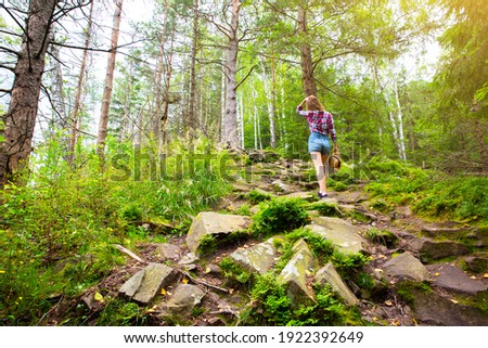 Hipster girl in the mountains. Stylish woman in straw hat and checkered shirt in forest. Wanderlust concept. Travelling and hiking in summer. mysterious wood. Beautiful nature.