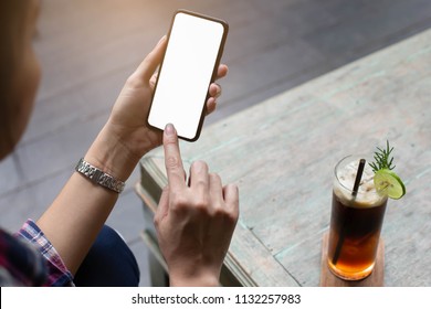 Hipster Girl Shopping Online In Phone At Cafe,selective Focus. She Wears A Silver Watch And Has Iced Coffee On Top Of Her.