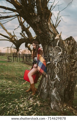 hipster girl standing near an old tree.